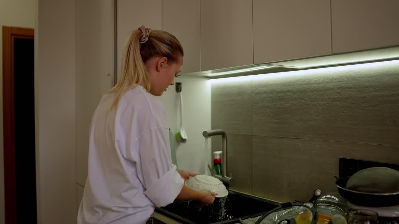 Kvinne som vasker opp i et kjøkken