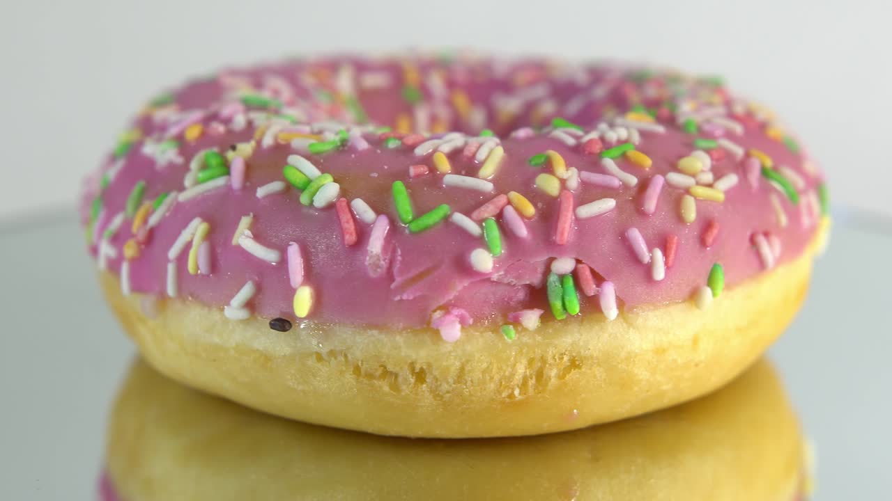 вращающиеся пончики с различными начинками на зеркальном столе. вкусный сладкий пончик, вращающийся на тарелке. яркий и красочный пончик крупный кадр макро, вращаящийся на белом фоне. бесшовная петля.