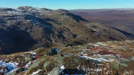 antena en órbita alrededor de un fotógrafo paisajista con teleobjetivo sentado en la cima de la montaña en noruega - primera nevada durante la temporada de otoño y vista hacia los valles de teigdalen y eksingedalen
