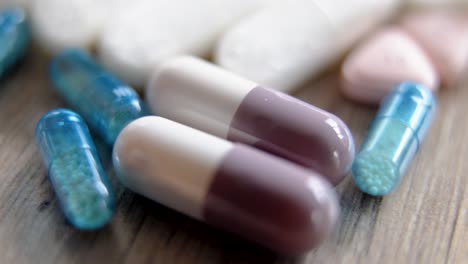 assorted capsules and pills with glossy coating resting on a wood surface in a healthcare context