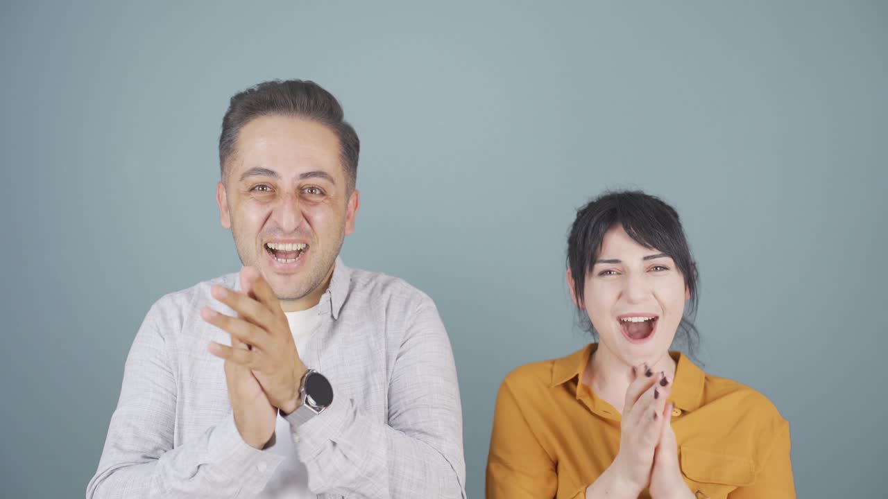 커플이 카메라를 향해 열정적으로 박수를 치고 있습니다.