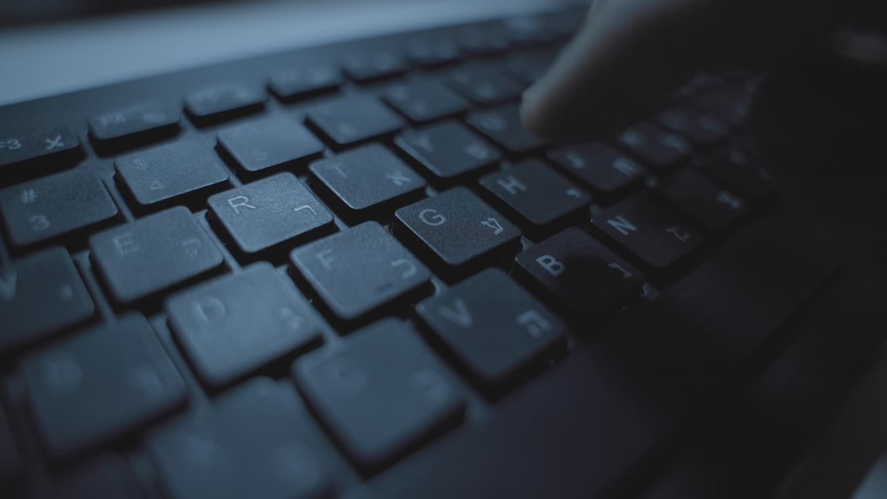 Close up on keyboard with Hebrew and English letter as hand typing on keys. Person coding or writing researching online. Pressing button and keypads. Business or dark web technology online. Desktop pc