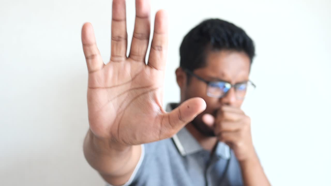 hombre tosendo y mostrando la señal de parada con la mano
