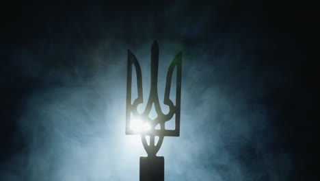 el escudo de armas de ucrania en la niebla, iluminado por un reflector