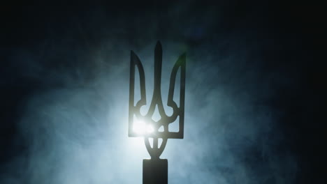 coat of arms of ukraine in the fog, illuminated by a spotlight