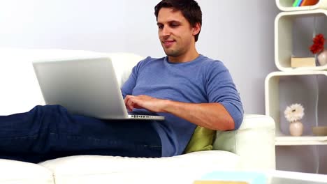 hombre tranquilo y casual usando su cuaderno sentado en el sofá