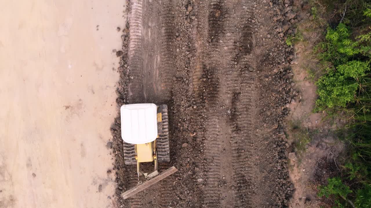 Luftfoto af en traktor og en grader, der jævner jorden ved opførelsen af et beboelseshus