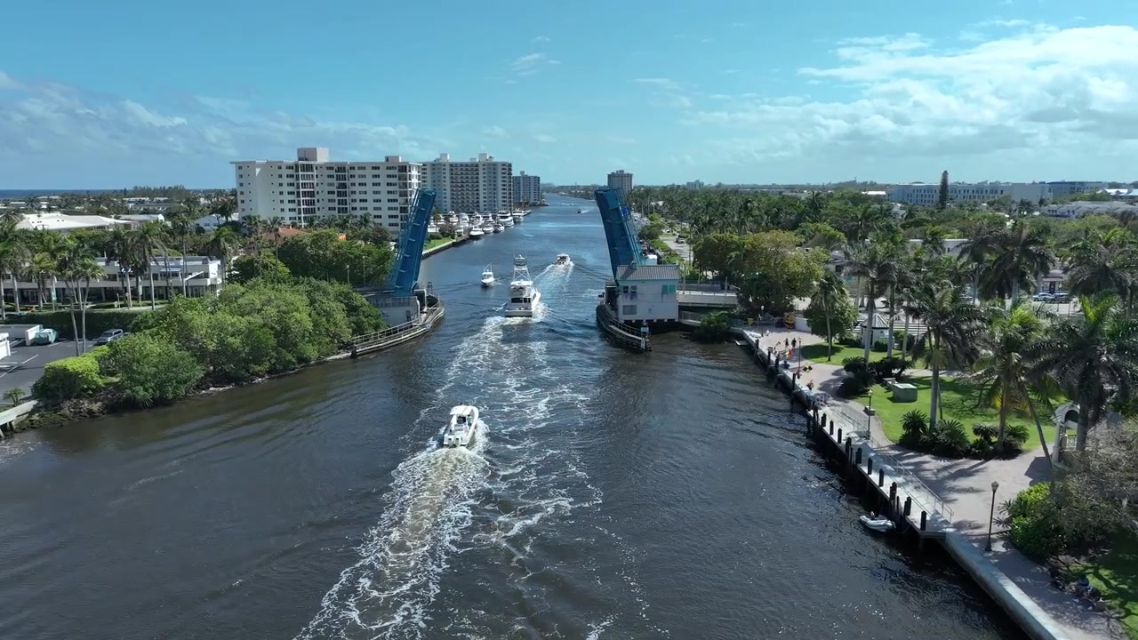 Drone seguindo barcos enquanto se aproximam da ponte levadiça aberta em Delray Beach, Flórida.
