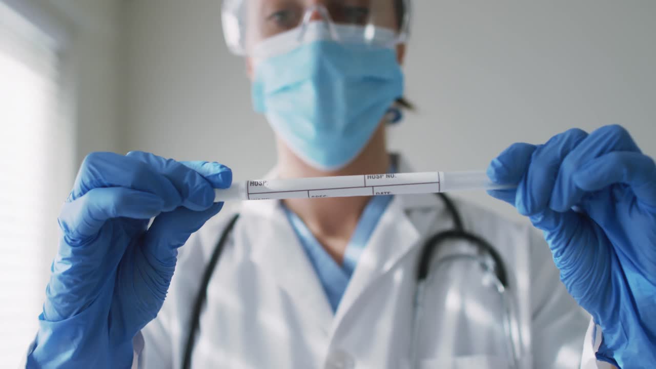 doctora caucásica que usa una máscara facial en casa con una prueba de swab