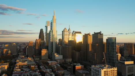 Aerial-drone-close-up-view-of-the-downtown-Philadelphia-skyline-featuring-tall,-glass-skyscrapers-at-sunset-with-golden-light-and-blue-summer-skies-showing-the-Comcast-Technology-Center