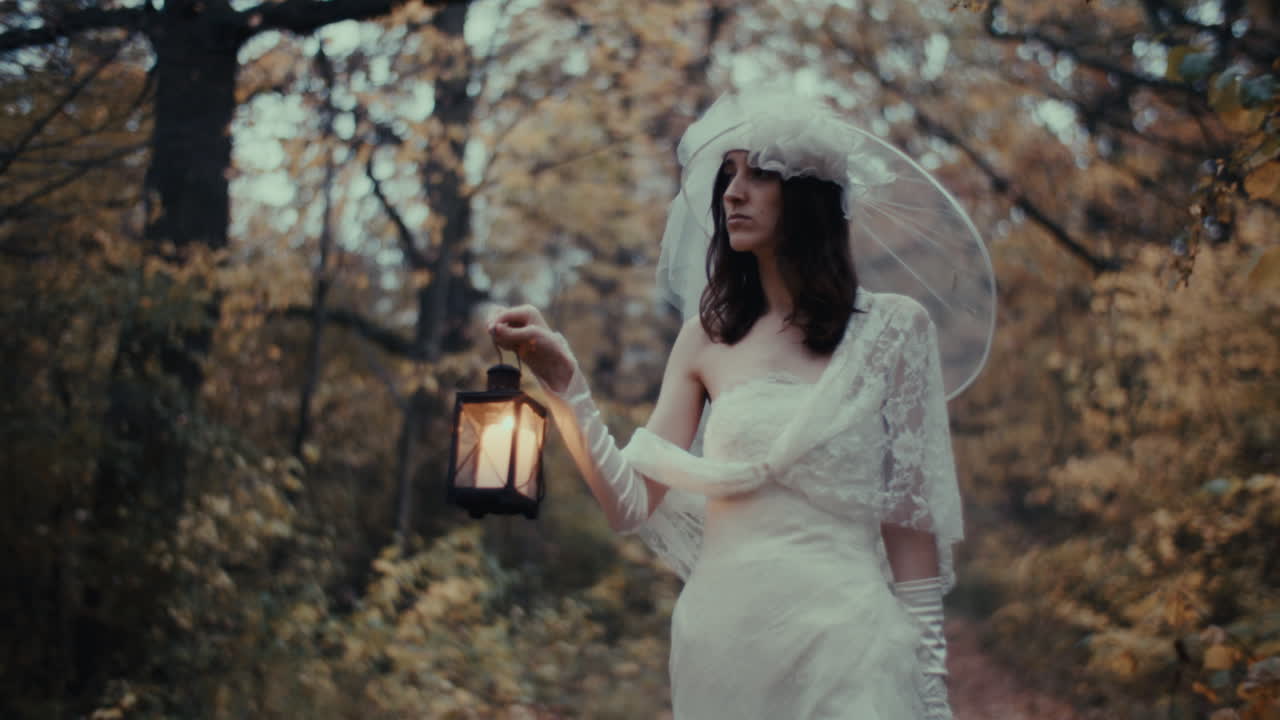 Donna eterea in abito da sposa con lanterna in un bosco autunnale