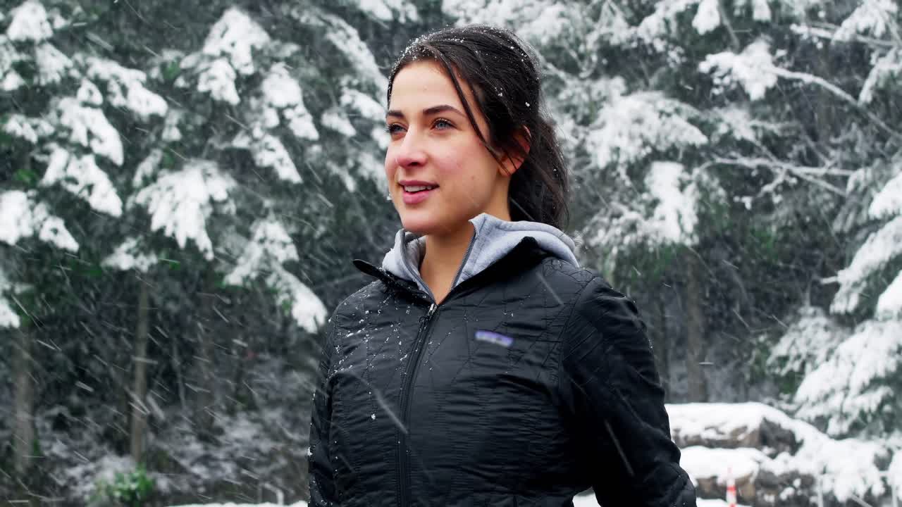 Smiling woman in jacket enjoying the snowfall