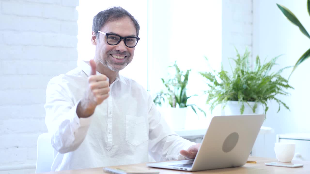 pulgares hacia arriba por un hombre de mediana edad en el trabajo, ambas manos