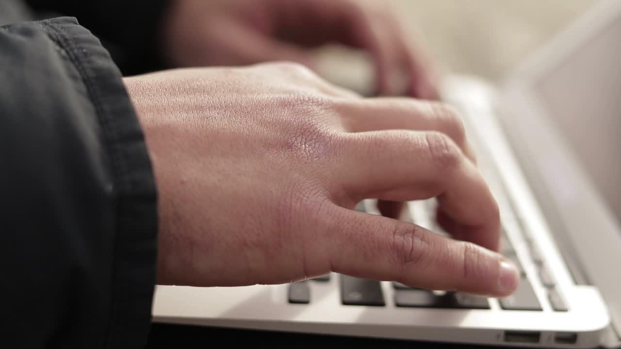 manos masculinas escribiendo en el teclado de un portátil