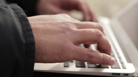 male hands typing on keyboard of laptop