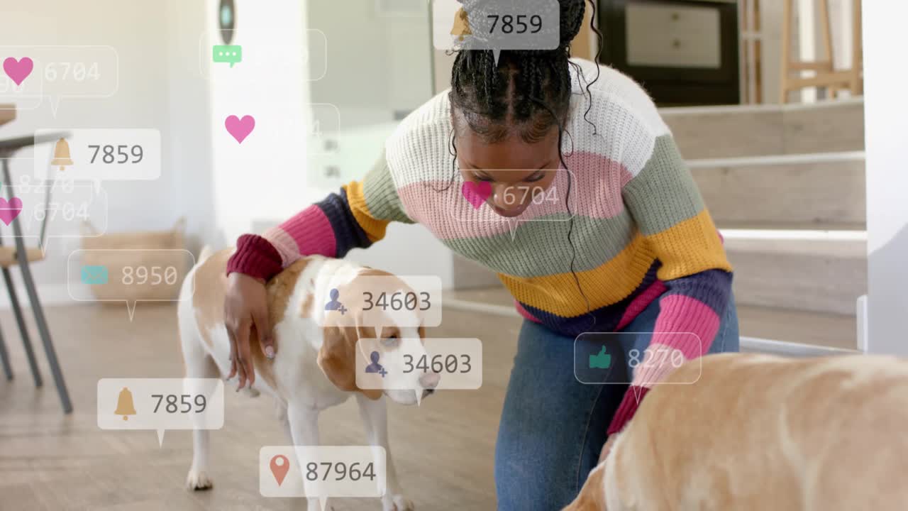 Woman kneeling in home, petting and rewarding dogs with treat, causing social media hearts floating