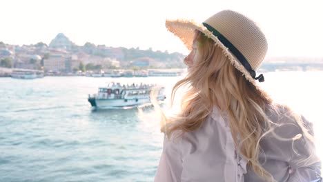 beautiful girl poses over galata bridge and enjoys view of bosphorus and suleymaniye mosque in istanbul,turkey