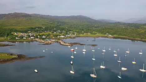 4k drone shot panning around boats on arisaig marina and flying towards village on west coast of scotland