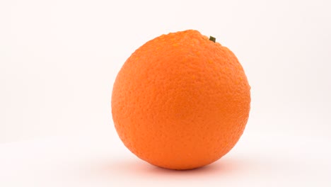 juicy orange fruit rotating on turn table. drops on the skin. isolated on white background. loopable. close up macro.