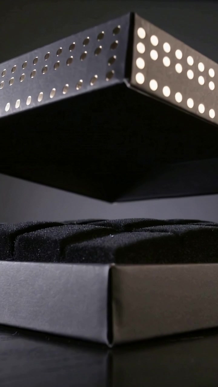 Vertical video: Lifting top lid of stacked black boxes on tabletop, revealing black liner inside