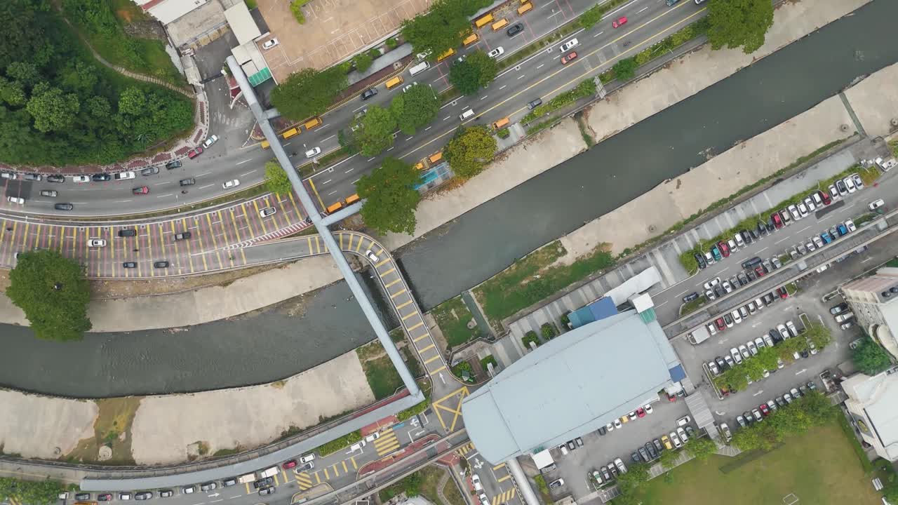Top-down aerial view of Kuala Lumpur, Malaysia, revealing downtown streets, traffic, river, and urban structures in a bustling city environment