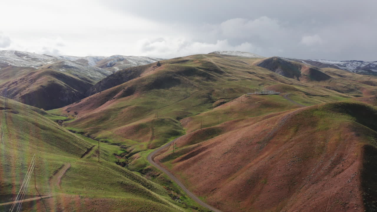 동부 오레곤 시골의 구불구불한 푸른 언덕 위를 날고, 구름 사이로 비치는 햇빛