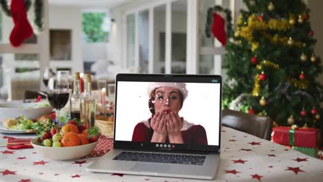 Glückliche-Kaukasische-Frau-Mit-Weihnachtsmütze-Auf-Laptop,-Die-Auf-Dem-Weihnachtstisch-Liegt