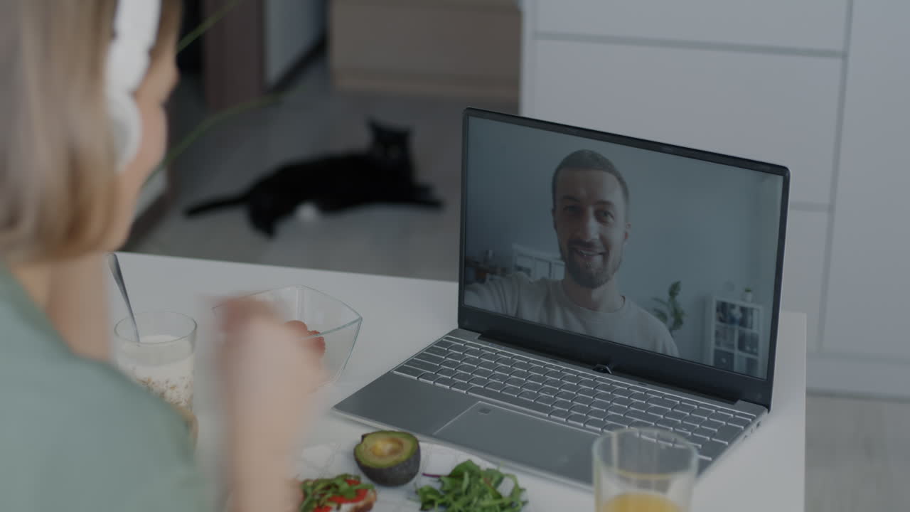 Woman having breakfast while video chatting with a man