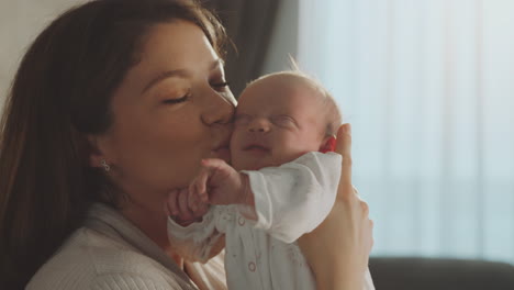 mother kissing her newborn baby