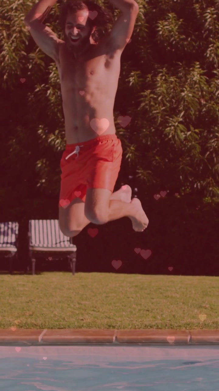 Video verticale: Uomo a torso nudo che corre verso la piscina e si tuffa per svago, creando uno schizzo con effetto bokeh a forma di cuore.