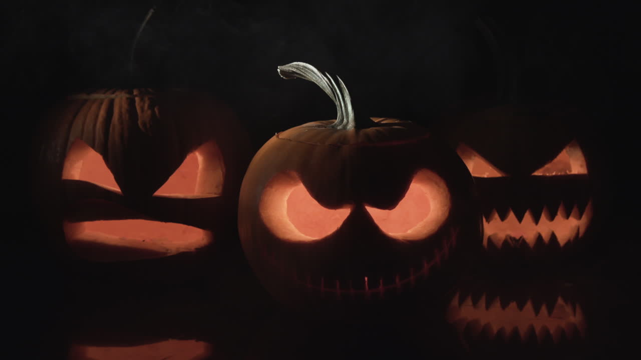 tres calabazas de halloween sobre fondo negro con soplo de humo, apple pro res