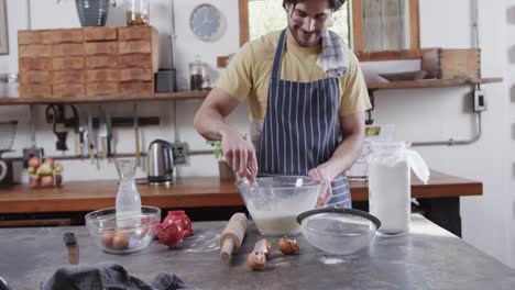 Hombre-Caucásico-Preparando-Masa-De-Pan-Usando-Tableta-En-La-Cocina,-Cámara-Lenta