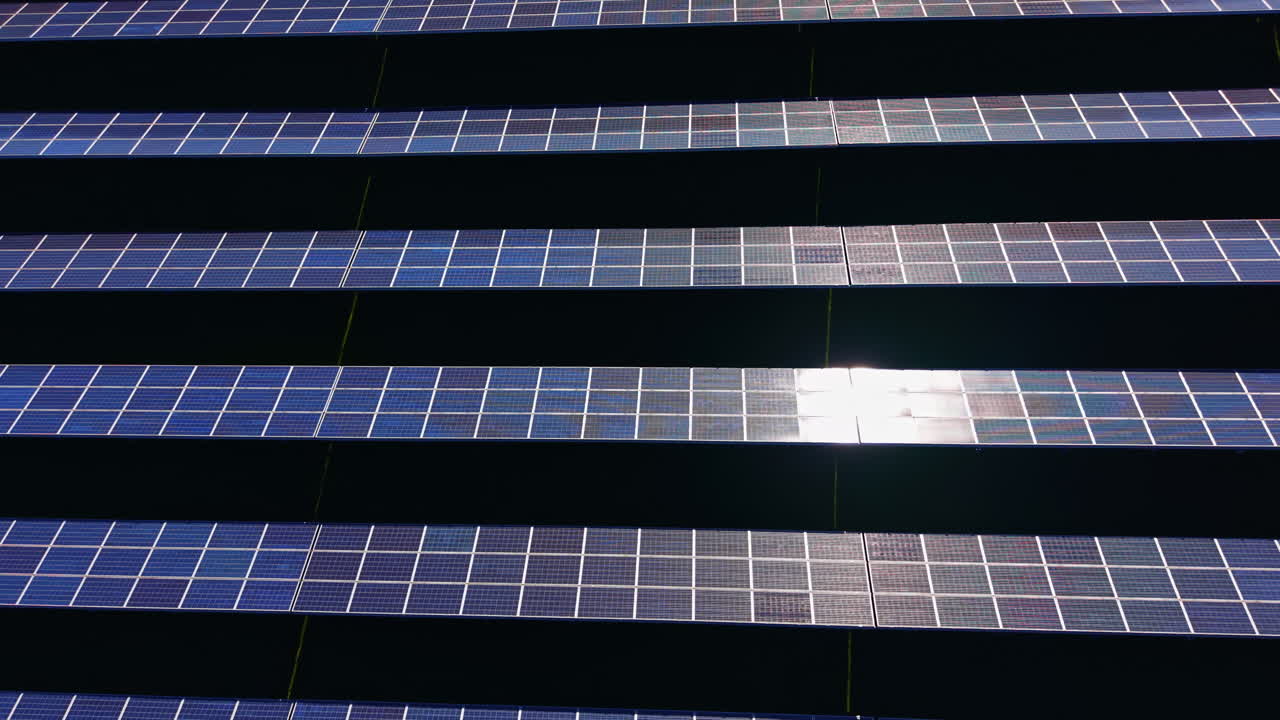 File di pannelli solari catturano la luce solare in un campo aperto situato in una zona rurale durante le ore pomeridiane per la produzione di energia pulita e gli sforzi di sostenibilità.