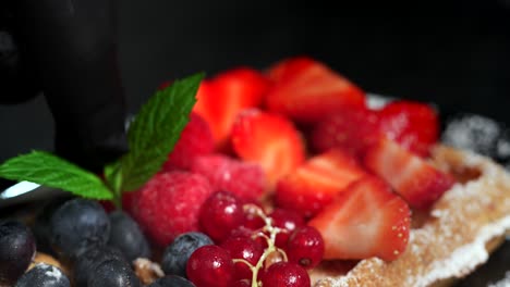 a sugared waffle with berries is garnished with mint