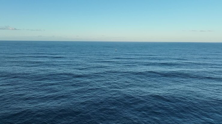 Ampia ripresa aerea di un singolo yacht a vela solitario nell'oceano, a vele spiegate.