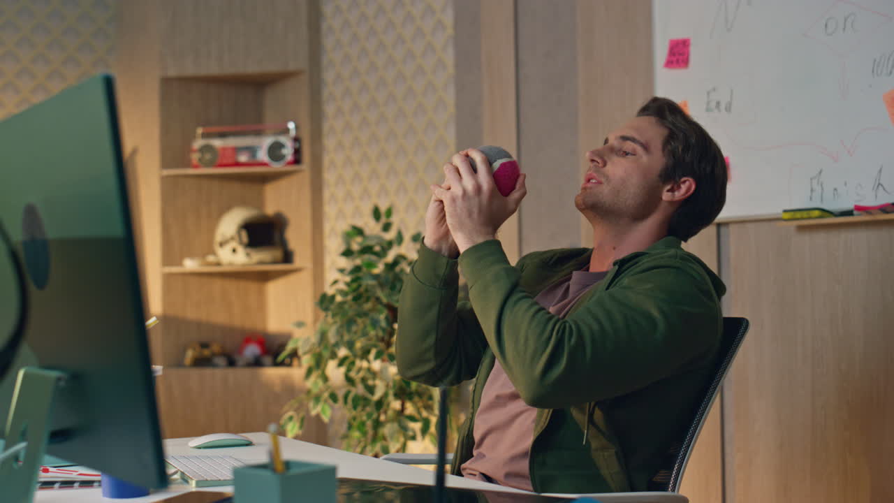 hombre con gafas lanzando juguete en la mesa de la computadora en primer plano. dos tipos dándole cinco