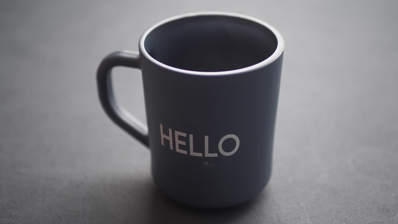 taza gris con la palabra hola