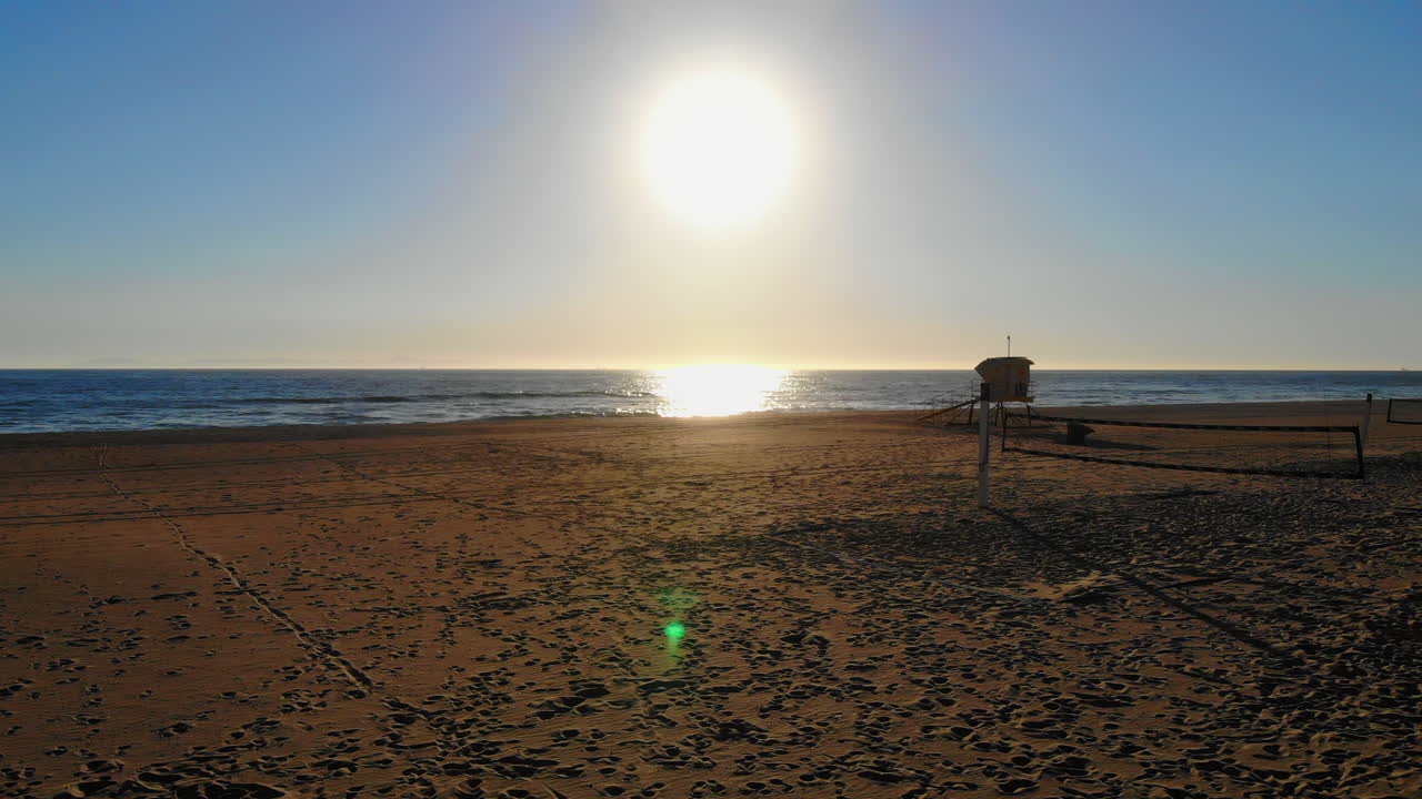 공중 드론 4k는 빈 배구 네트 위로 아름다운 남부 캘리포니아 해변 일몰과 파도로 날아갑니다.