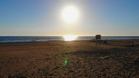 drone aéreo 4k vuela sobre redes de voleibol vacías hasta la hermosa puesta de sol en la playa del sur de california y las olas del océano