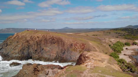 aerial drone view over the look at me now headland bay, with people on top, at the emerald beach, in australia