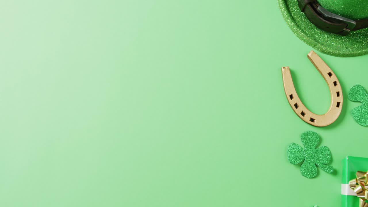 Video of st patrick's green shamrock leaf, horse shoe, hat with copy space on green background