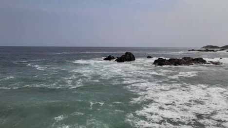 Volando-Sobre-Las-Olas-Con-Vista-A-Las-Rocas-En-Mazunte,-Oaxaca,-México