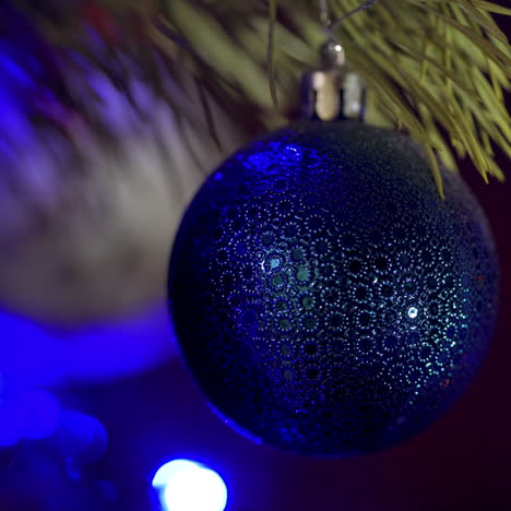 big blue bauble on pine tree at christmas. christmas and new year decoration. christmas ball on the background of twinkling lights. beautiful shiny christmas toy on a spruce tree. close-up.