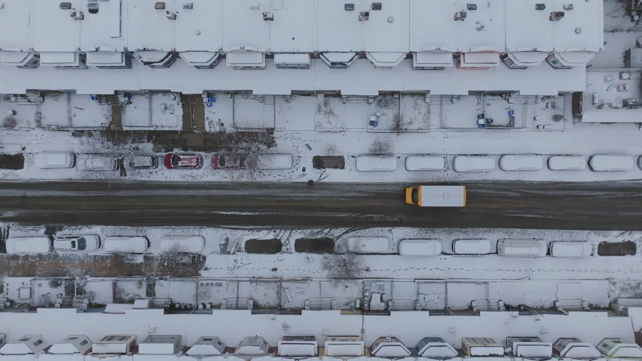 Top down aerial footage of a school bus waiting for a student in snow covered neighborhoods in West Philadelphia, Pennsylvania.