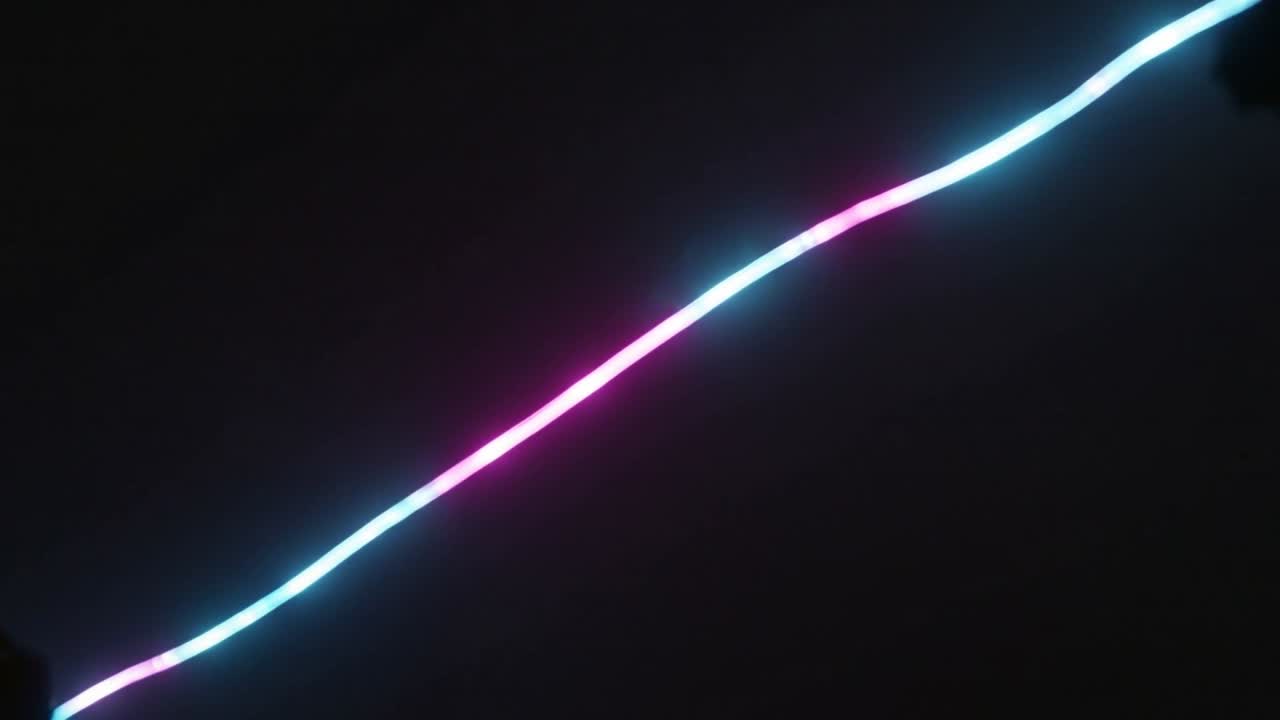 Estela de neón cambiante deslizándose hacia la parte superior derecha sobre un fondo negro, formando un resplandor cian-magenta y halos.
