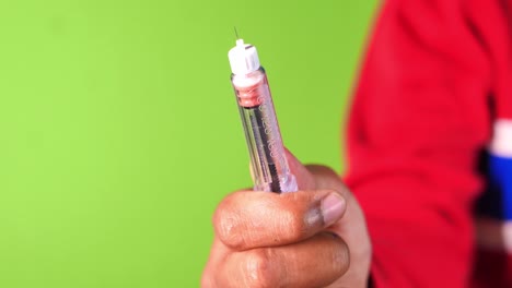 hand holding insulin pen on green background