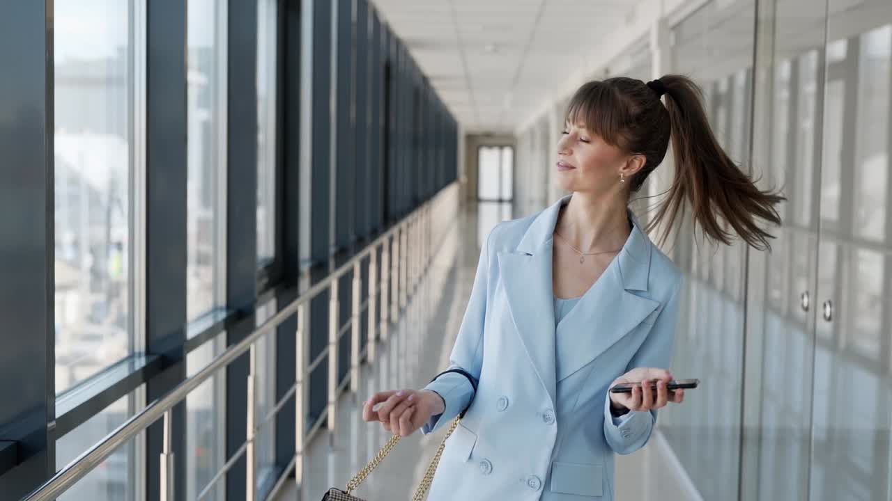 pretty girl in a stylish suit dancing with a smartphone in her hands