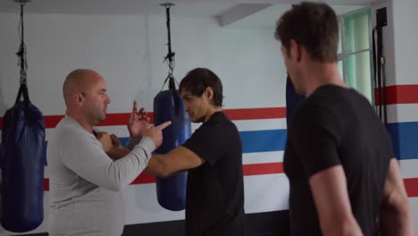 caucasian coach giving advice to two athletes in boxing gym