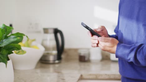 video de la sección media de un hombre de dos razas usando un teléfono inteligente en la cocina