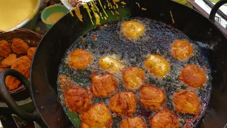 popular hot indian snacks called 'alu besan chop' and 'dhaniya patta pakora' being fried in hot oil